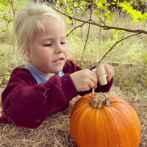 girl trying to pierce a hole on a pumpkin