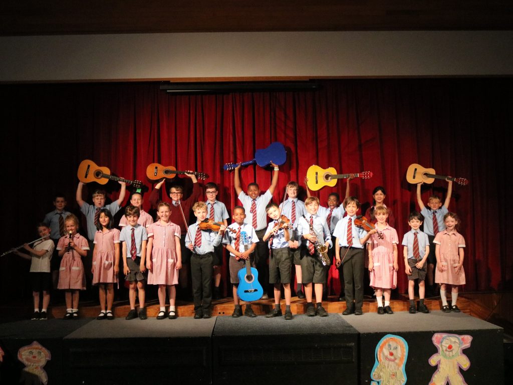 A group of students holding up acoustic guitars in the air