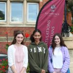Three girls standing beside GCSE results day banner