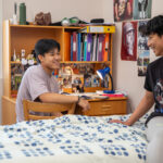 Two boys chatting in boarding school bedroom