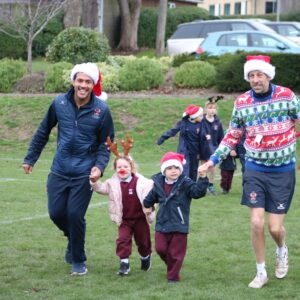 Children running santa run with adult helpers